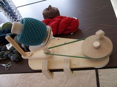 a wooden skateboard sitting on top of a table next to knitting supplies and yarn