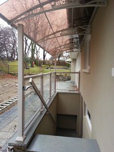 an outdoor covered walkway next to a building with trees in the background and grass on the ground