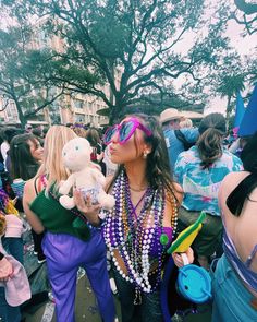 a woman holding a stuffed animal in her arms at a festival with other people standing around