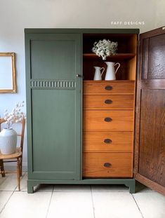 a green cabinet with two vases on top of it next to a wooden chair