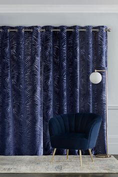 a blue chair sitting in front of a curtain