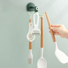 three spoons and two spatulas hanging on a wall