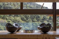 two modern chairs sitting on top of a wooden floor next to a window with mountains in the background