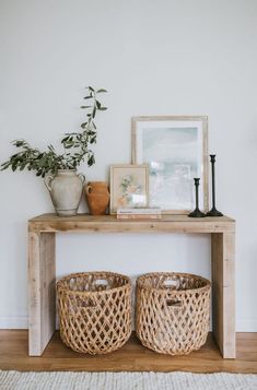 two wicker baskets sit on top of a wooden shelf next to a potted plant