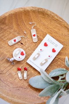 a wooden table topped with lots of different types of earrings and brooches on top of it