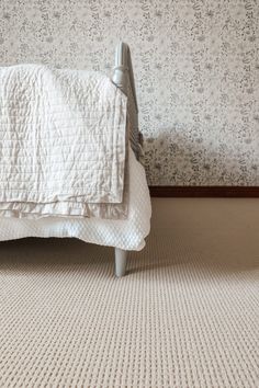 a white bed sitting on top of a carpeted floor