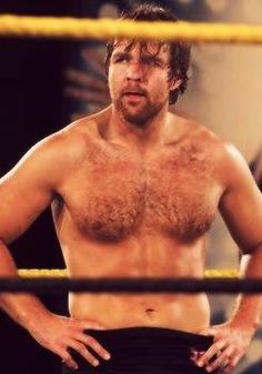 a shirtless man standing in front of a wrestling ring with his hands on his hips