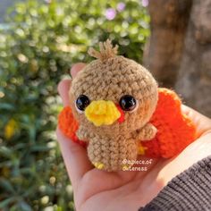 a hand holding a small stuffed bird in it's palm