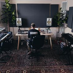 a man sitting at a desk in front of a sound board with speakers on it