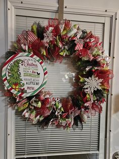 a christmas wreath hanging on the front door with candy canes and ribbon around it