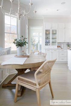 a dining room table with two chairs and a potted plant