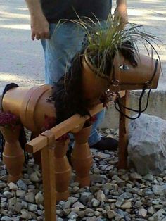 a man standing next to a wooden horse planter