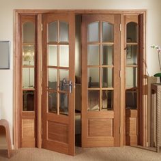 an empty room with wooden doors and carpeted flooring in front of two windows