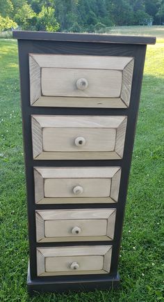 a black and white dresser sitting in the grass