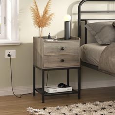 a nightstand with two drawers next to a bed and a window in a room that has a rug on the floor