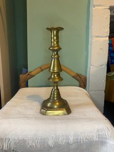 a brass candle holder sitting on top of a white table cloth covered ottoman in a living room