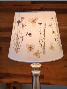 a lamp that is on top of a wooden table with flowers painted on the lampshade