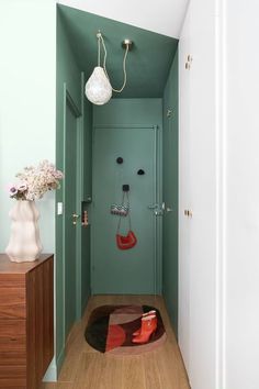 a bathroom with green walls and wooden floors, including a door leading to the toilet