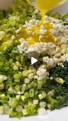 a bowl filled with chopped vegetables and dressing being poured into the salad mixture to make it