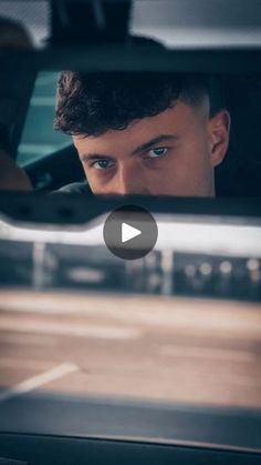 a man is driving in the back seat of a car and looking at his reflection