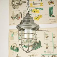 an old light hanging from the ceiling in front of a wall with diagrams on it