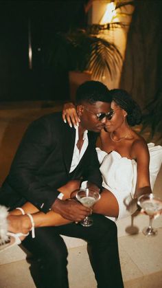 a man and woman sitting next to each other holding wine glasses