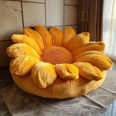 a large yellow flower sitting on top of a bed