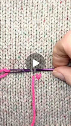 someone is knitting with pink yarn on the side of a knitted sweater, and there is a video demonstrating how to crochet