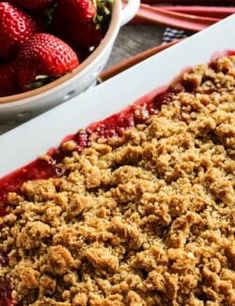 strawberry crumbled dessert sitting on top of a table next to bowls of strawberries