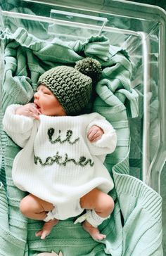 a baby in a crocheted outfit laying on top of a blanket