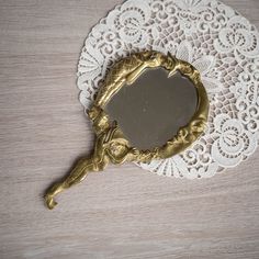 a mirror sitting on top of a white doily next to a wooden tablecloth