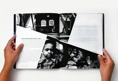 two hands holding an open book with black and white photos