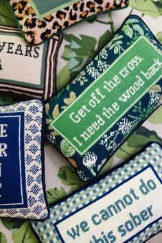 four cross stitch pillows with different sayings on them, all in blue and green