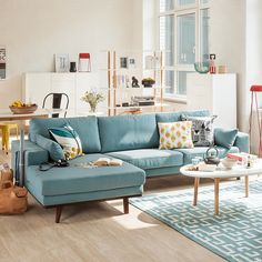 a living room filled with lots of furniture next to a large window on top of a hard wood floor