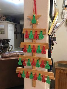 a christmas tree made out of wooden pegs is hanging on the side of a wall