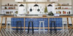 a kitchen with blue and white tiles on the floor, counter tops and shelves filled with cooking utensils