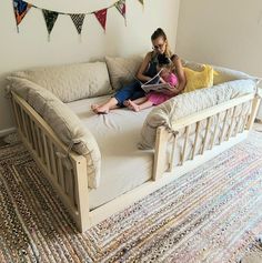 a woman sitting on top of a couch next to a baby in a crib