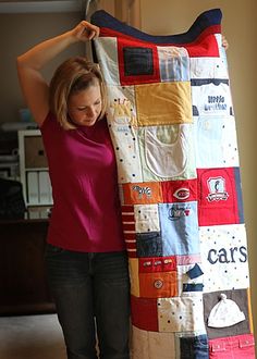 a woman is holding up a colorful quilt