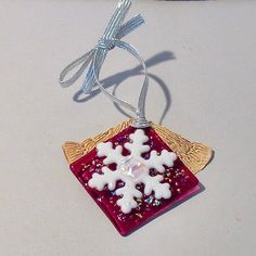 a glass ornament with snowflakes hanging from it's side on a table