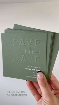 a hand holding up two green save the date cards