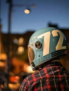 a person wearing a motorcycle helmet with the number twelve on it's face and looking off into the distance