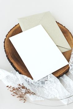 an empty card and envelope on a wood slice with lace, flowers and twine