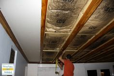 a man in an orange shirt is working on the ceiling