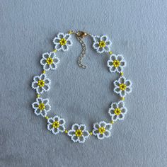 a bracelet with yellow and white beads on a gray surface, in the shape of flowers