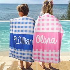 two children wrapped in personalized towels sitting by the pool looking out at the ocean