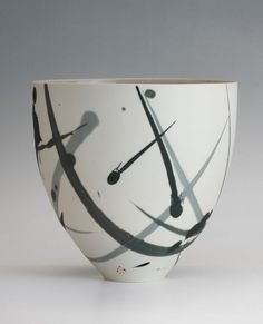 a white bowl with black and white designs on the inside is sitting in front of a gray background