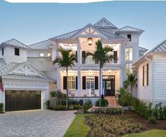 a large white house with palm trees in the front yard