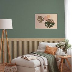 a living room with a white couch and green walls, wooden flooring and a painting on the wall