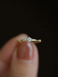 a hand holding a diamond ring in it's left hand with the other hand