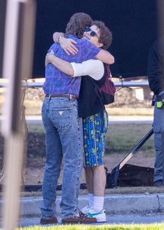 two people hugging each other on the street